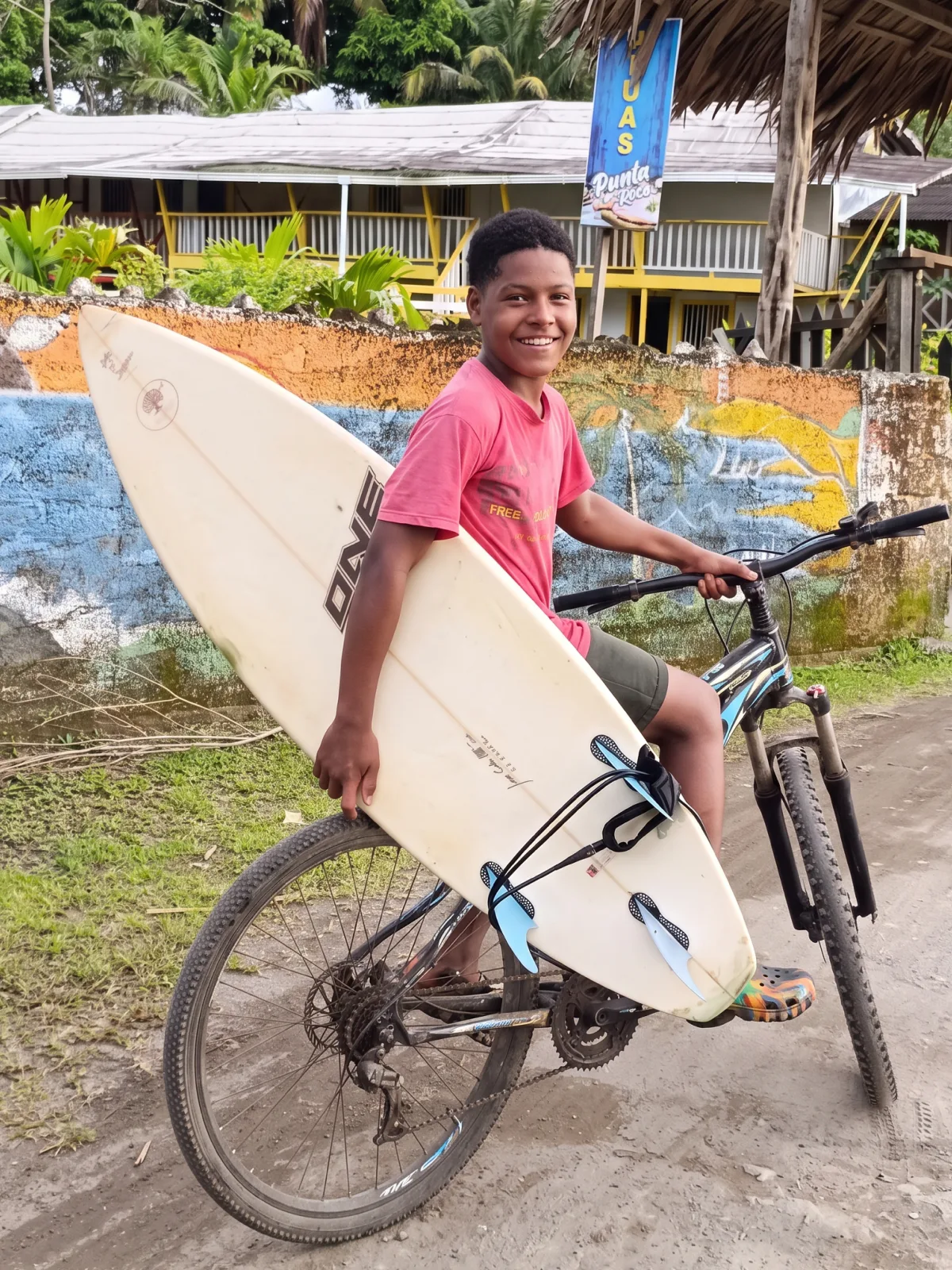 Joven surfista en bicicleta con su tabla bajo el brazo